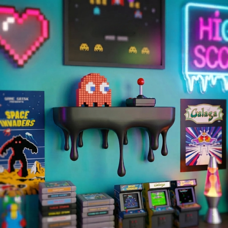 A retro-themed room scene featuring a black wall-mounted shelf with a dripping design, holding a pixelated orange-red character toy and a vintage arcade joystick. The wall is decorated with neon-style signs, framed retro posters, pixel art, and several arcade game cabinets and cartridges at the bottom.