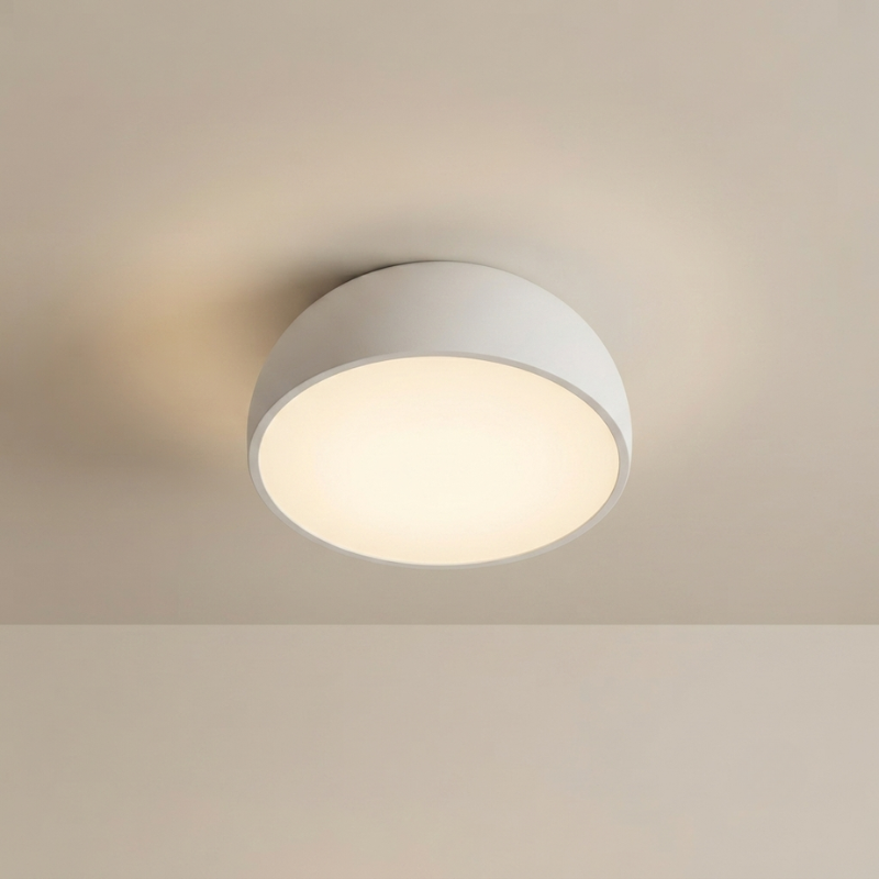 A modern flush-mount ceiling light fixture with a matte white semi-spherical shade and a glowing warm white frosted diffuser, shown installed on a matching beige ceiling.