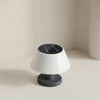 A modern mushroom-shaped solar table lamp with a glossy white shade, dark gray base, and a black solar panel on top, set against a minimalist beige background.