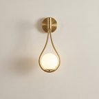 Gold wall sconce with a round light bulb on a beige background