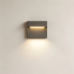 A modern square wall-mounted light fixture with a dark gray textured finish, emitting a warm yellow light downward against a plain off-white wall.