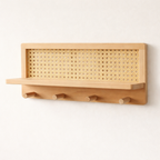 Wooden wall-mounted rack with woven top section and hooks on a white background