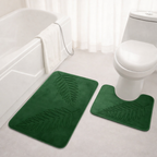 Green bath mat with leaf pattern on a bathroom floor.
