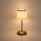 Table lamp with a gold base and beige shade on a neutral background