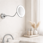 Wall-mounted makeup mirror with a light above a bathroom sink.