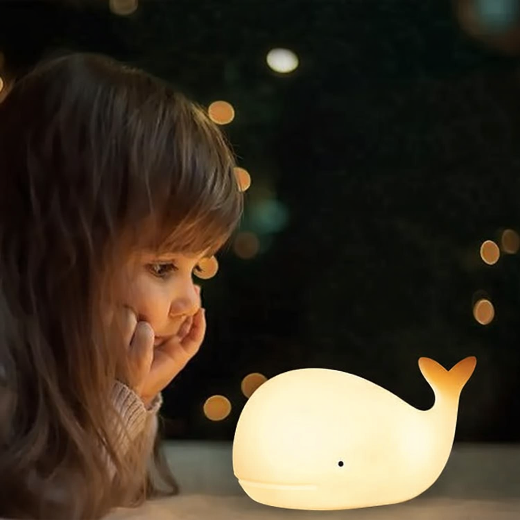 Child looking at a whale-shaped night light with a dark, bokeh background
