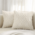Two textured cream pillows on a sofa with a neutral background