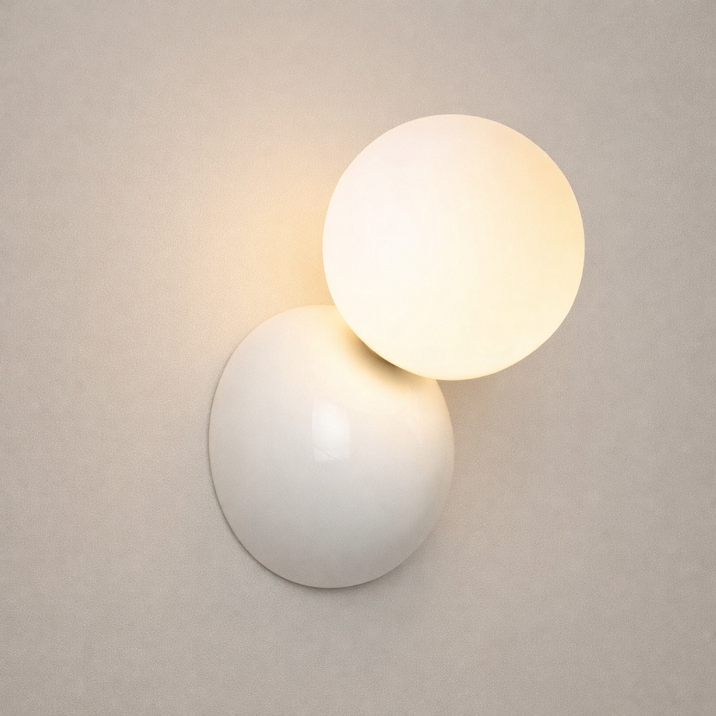 Wall-mounted light fixture with two spherical shades on a neutral background