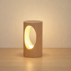 Wooden cylindrical lamp with a warm glow on a wooden surface.