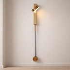 Modern wall lamp with gold fixture and black cable on a neutral wall.
