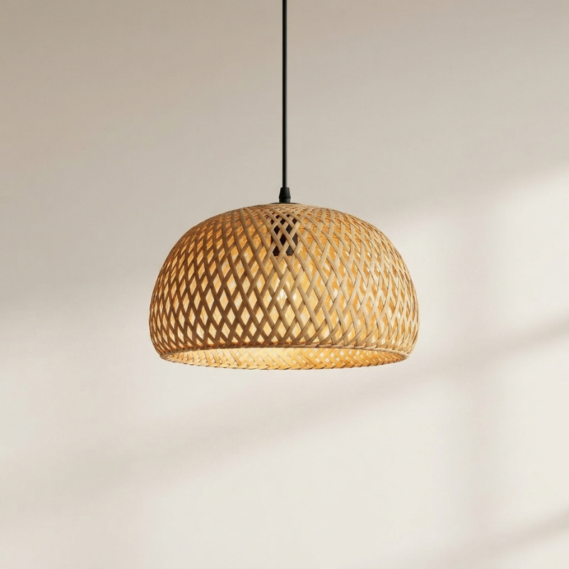 A dome-shaped pendant light with a natural woven rattan shade suspended by a black cord against a warm off-white wall.