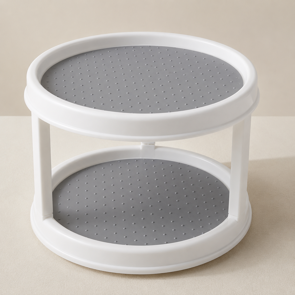 A two-tier round plastic organizer with a white frame and gray perforated shelves, shown on a neutral beige background.