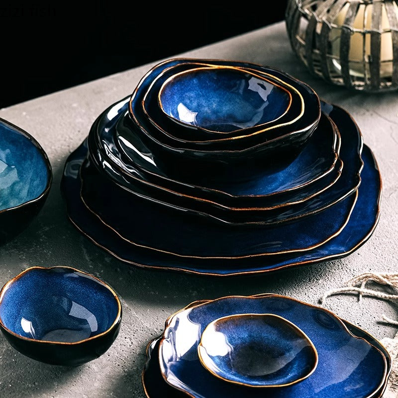 Set of blue ceramic dishes with gold rims on a gray surface
