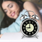 Alarm clock on a table with a blurred background of a person lying down