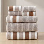 Stack of brown and beige striped towels on a wooden surface with a neutral background