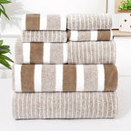 Stack of brown and beige striped towels on a white surface with a plant in the background