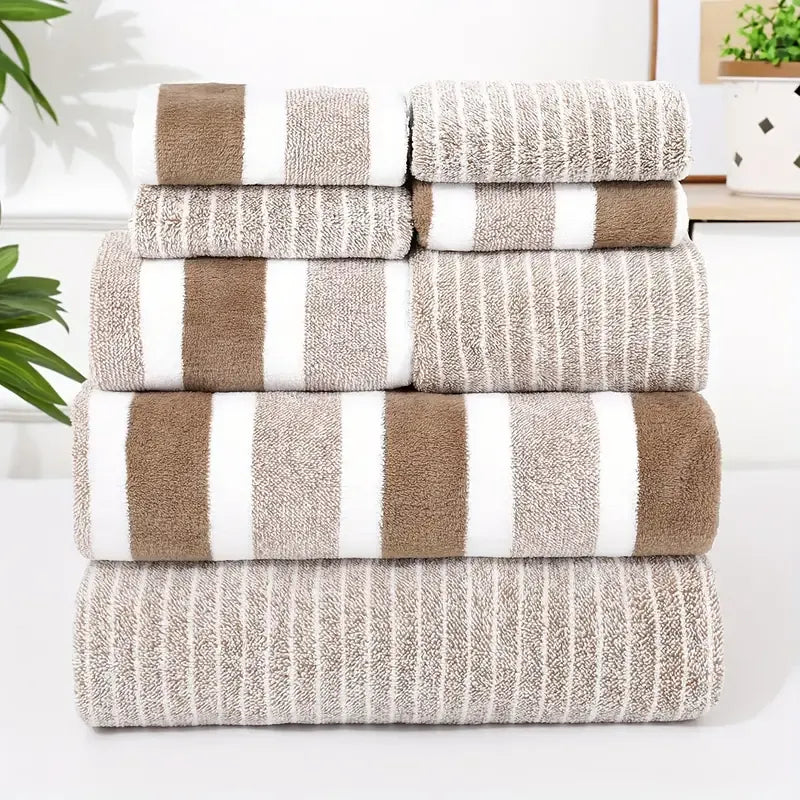 Stack of brown and beige striped towels on a white surface with a plant in the background
