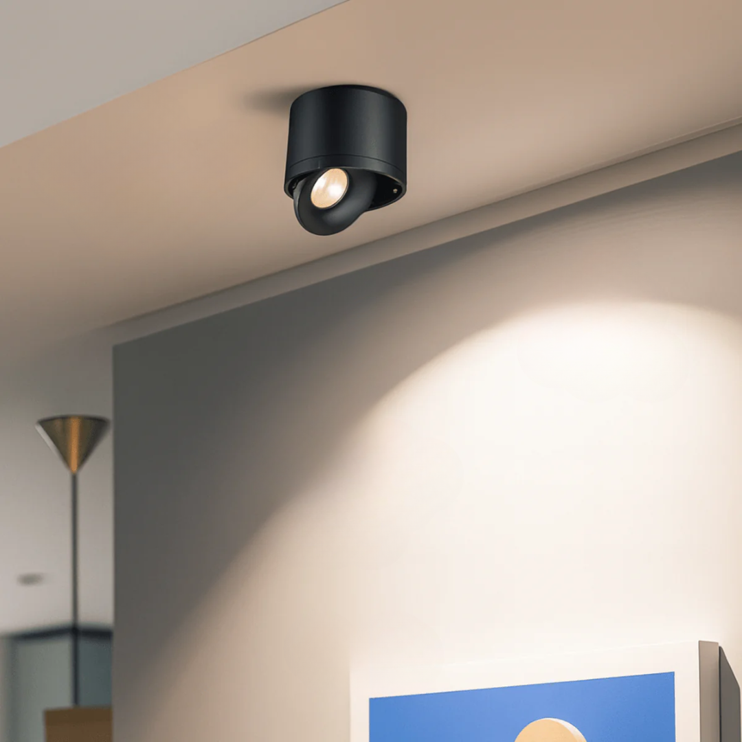 Black ceiling light fixture on a beige ceiling with soft glow on wall