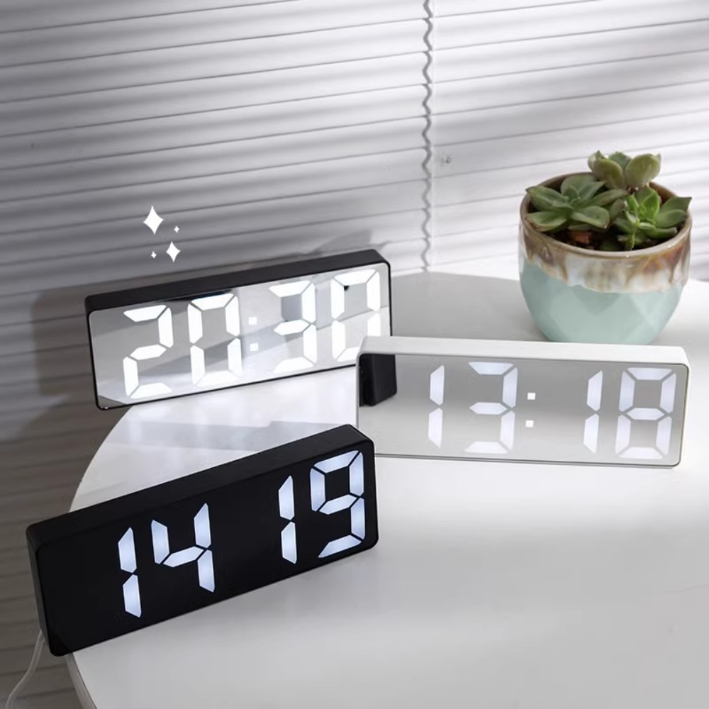 Digital clocks on a table with a plant in the background