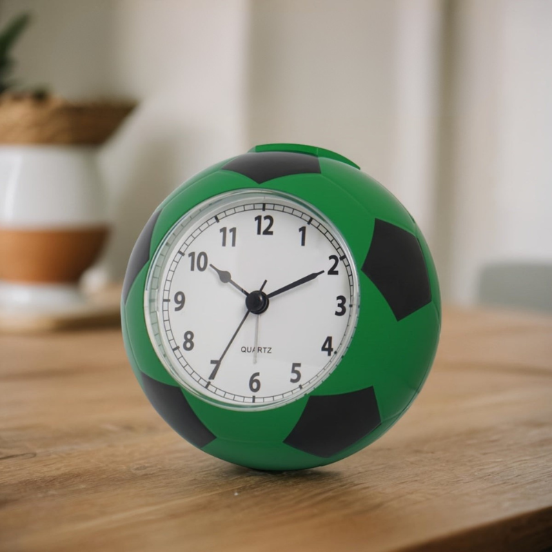 Green and black soccer ball clock on a wooden surface with a blurred background