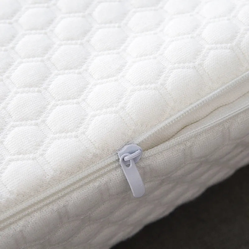 Close-up of a white quilted mattress cover with a zipper.