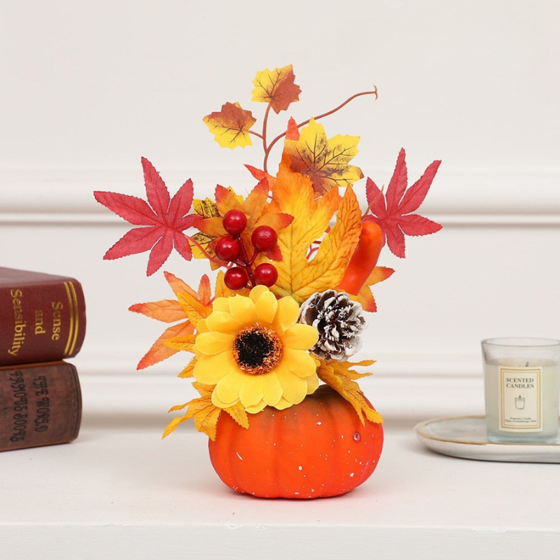 Decorative pumpkin with autumn leaves and berries on a white surface.