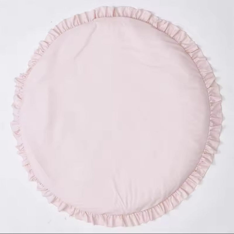 A round light pink fabric cushion with a ruffled edge, photographed flat against a plain white background.