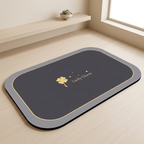 Gray bath mat with gold border and 'Lucky Charm' text on a light wooden floor.
