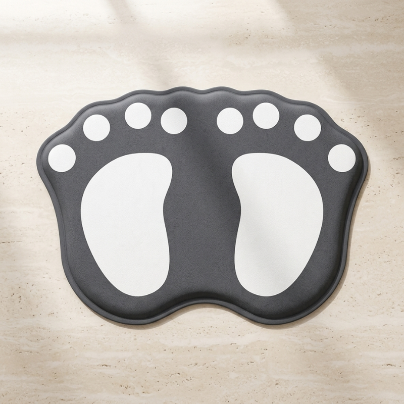 Black foot-shaped mat with white accents on a beige surface