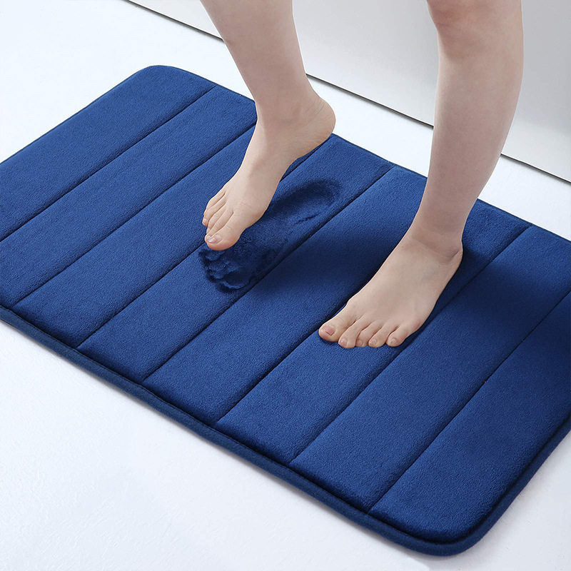 Blue bath mat with a person stepping onto it on a white floor.