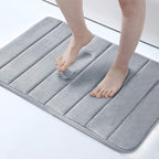 Person stepping onto a gray bath mat on a white floor