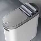 White trash bin with gray lid and three gray cylindrical liners on a tiled floor.