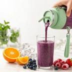 Purple smoothie being poured from a green blender into a glass, with fruits and glasses on a light surface.
