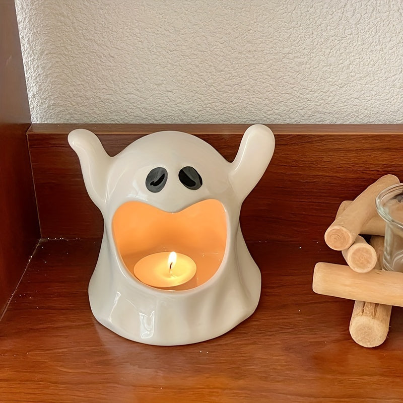 A cute ghost-shaped ceramic candle holder with a lit tea light candle inside, sitting on a wooden shelf next to a small wooden campfire accessory.