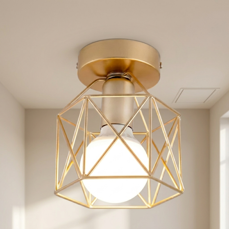 A modern semi-flush mount ceiling light fixture with a gold-finished geometric wireframe cage and a glowing white globe bulb, shown installed on a beige ceiling.