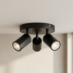 Black ceiling light fixture with three cylindrical lights on a neutral background