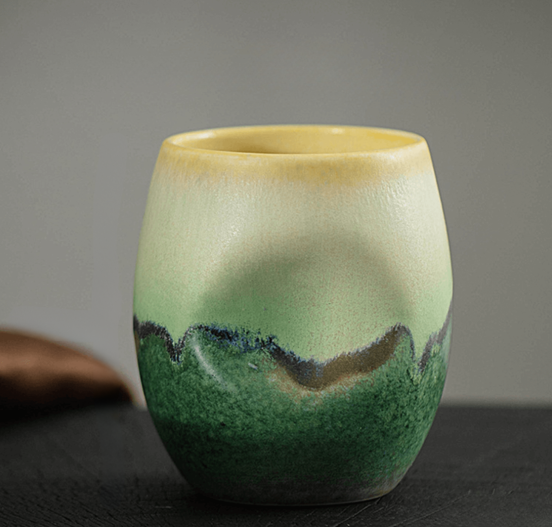 Ceramic cup with green and beige gradient on a dark surface