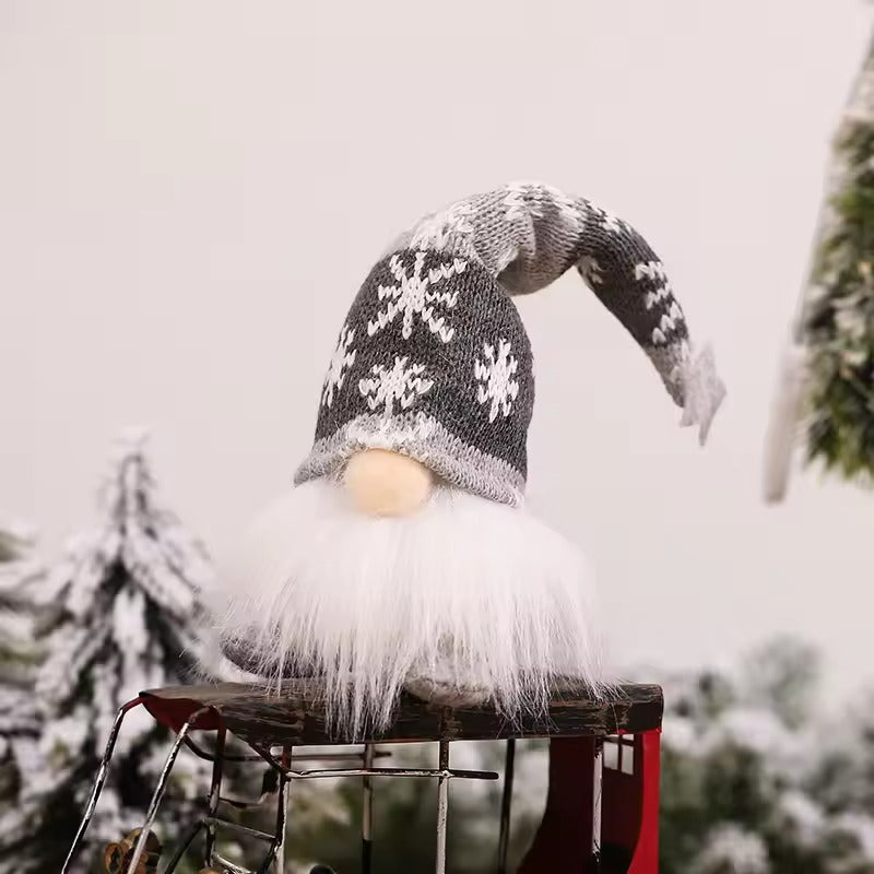 Decorative gnome with a gray knit hat on a wooden stool against a snowy background