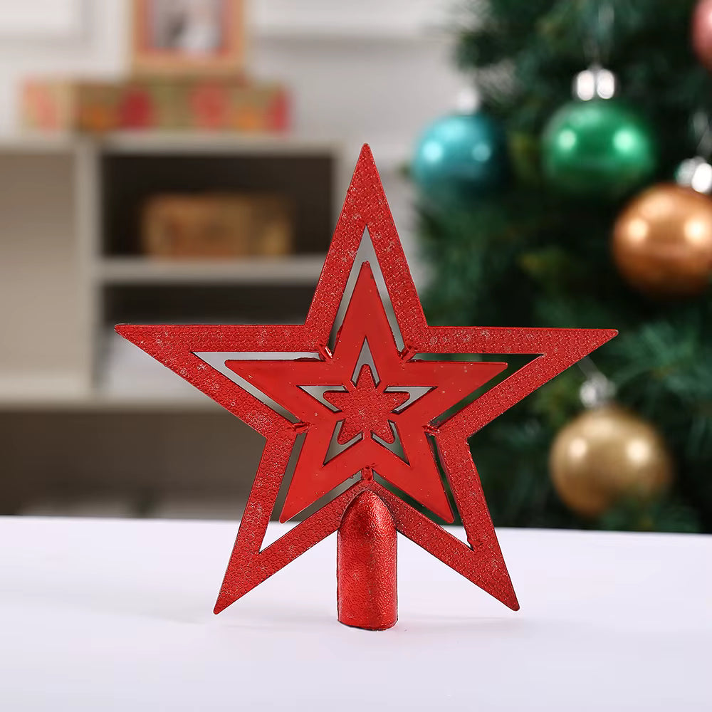 A red glittery star-shaped Christmas tree topper with a matching red cylindrical base, displayed on a white surface with a blurred Christmas tree in the background.