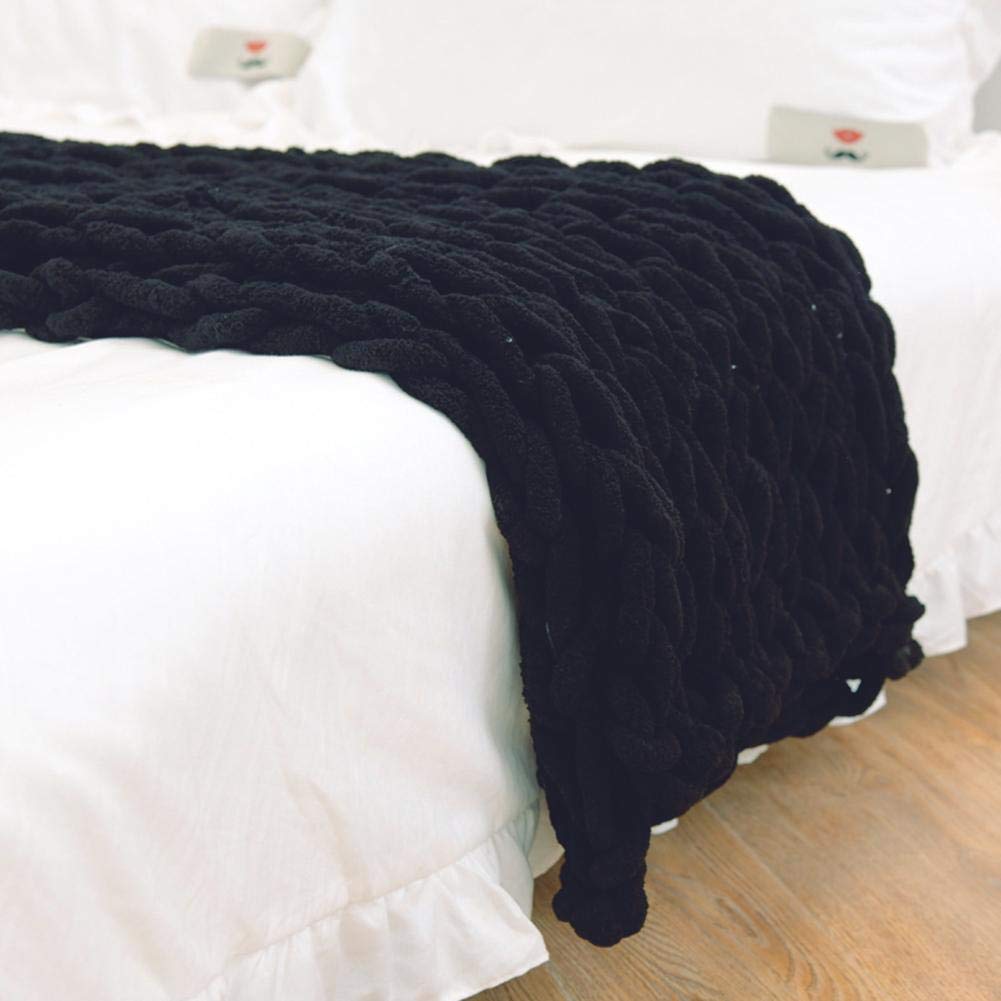 Black knitted blanket draped over a white bed