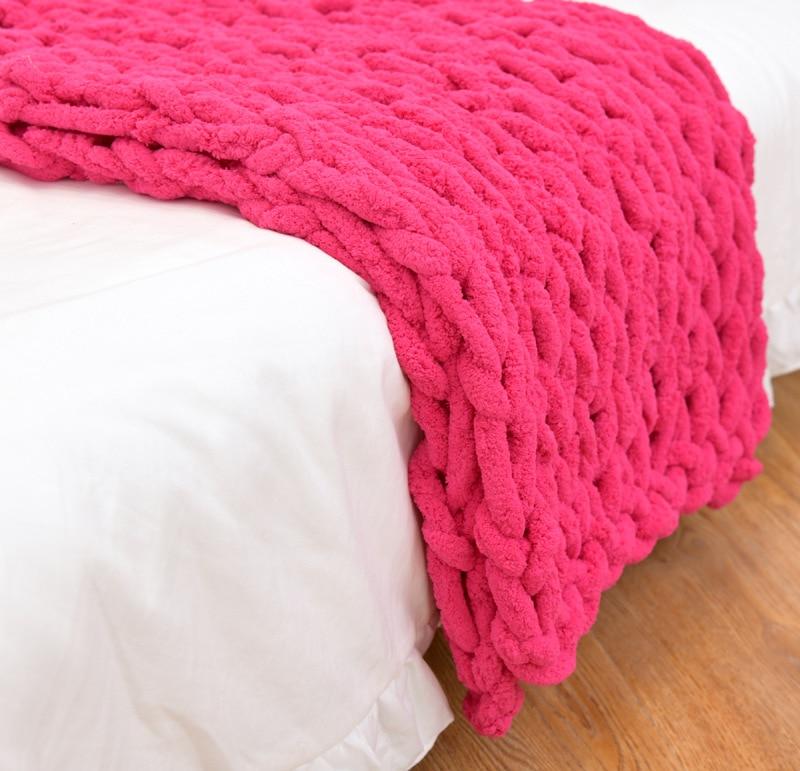 Pink knitted blanket draped over a white surface