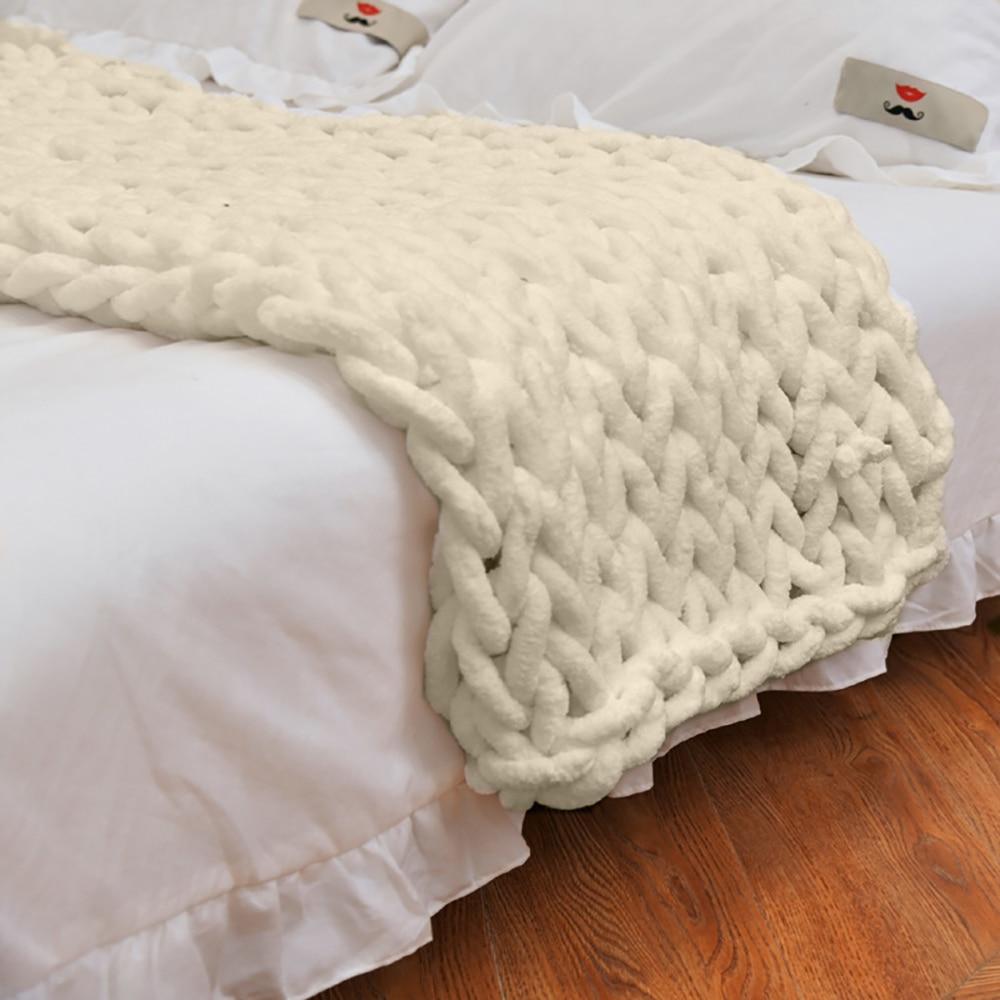 White chunky knit blanket draped over a bed with white bedding.