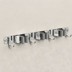A wall-mounted chrome hook rack with six evenly spaced metal hooks on a light beige textured wall.