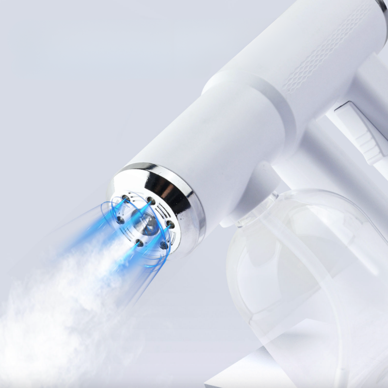A close-up of a white handheld steam cleaner or steam spray device with a clear plastic cup holder and a blue mist jet coming out of the nozzle, shown on a light gray background.