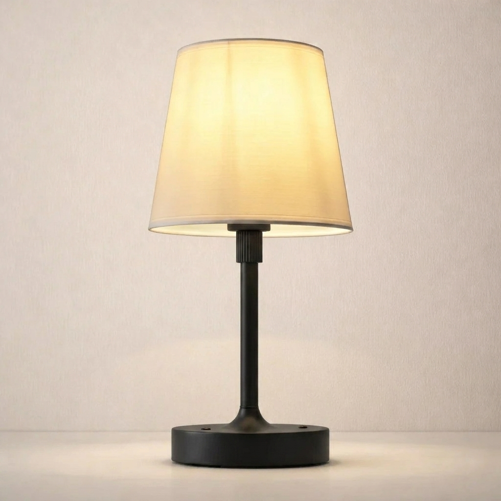 Table lamp with a beige shade and black base on a neutral background