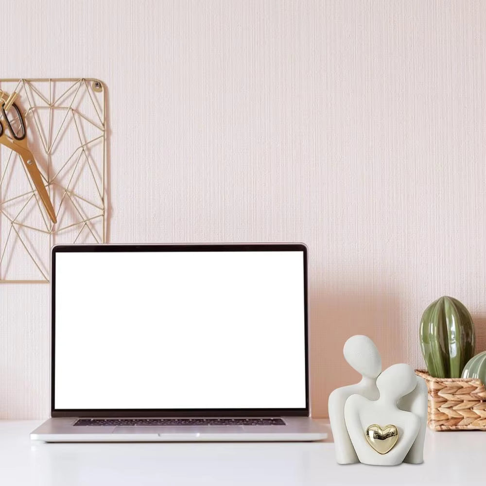 Laptop on a desk with decorative items including a heart-shaped object and a cactus.