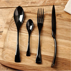 Set of black cutlery including spoon, fork, and knife on a wooden surface