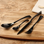 Set of black cutlery including a spoon, knife, and fork on a wooden surface.