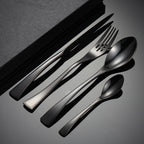 Set of black cutlery including knives, forks, and spoons on a dark surface.
