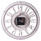 A round wall clock shown from the back, featuring a white outer frame with cutout Roman numerals and a visible black and white mechanical movement mechanism in the center.